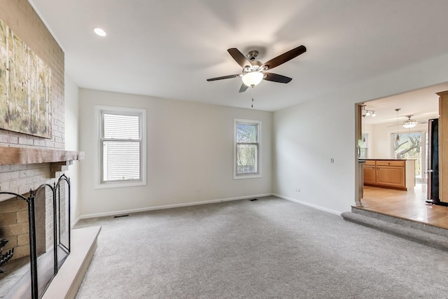 unfurnished living room with ceiling fan, light carpet, baseboards, and a fireplace
