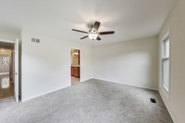 empty room with visible vents, a ceiling fan, baseboards, and light carpet