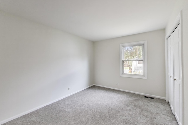 unfurnished bedroom featuring visible vents, carpet, baseboards, and a closet