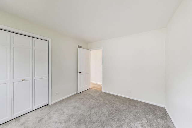 unfurnished bedroom with baseboards, visible vents, a closet, and light colored carpet