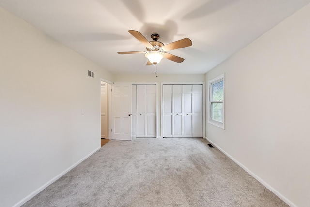 unfurnished bedroom with baseboards, multiple closets, carpet, and visible vents