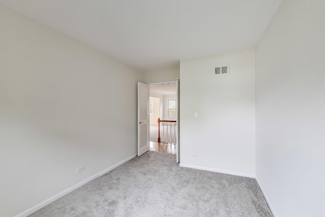 carpeted spare room featuring baseboards and visible vents