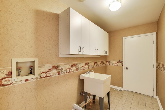 laundry area featuring light tile patterned floors, washer hookup, cabinet space, and visible vents