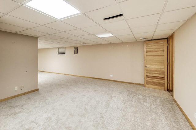 finished below grade area with baseboards, carpet flooring, and a drop ceiling