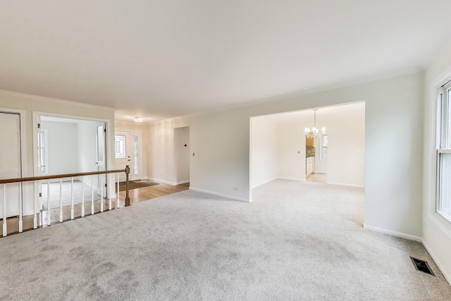 unfurnished room with visible vents, baseboards, a chandelier, and light carpet