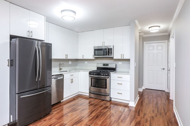 kitchen with a sink, light countertops, ornamental molding, stainless steel appliances, and dark wood-style flooring