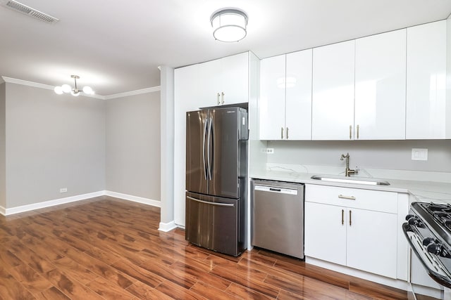 kitchen featuring visible vents, a sink, dark wood-style floors, appliances with stainless steel finishes, and crown molding