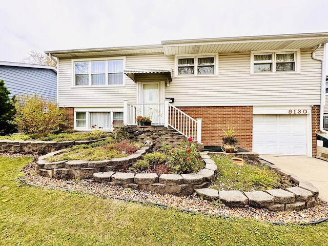 split foyer home featuring a garage, concrete driveway, and brick siding