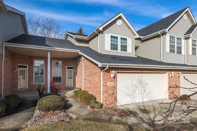 view of front facade featuring covered porch, a shingled roof, concrete driveway, a garage, and brick siding