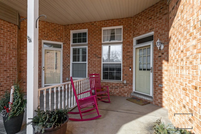 view of exterior entry with covered porch and brick siding