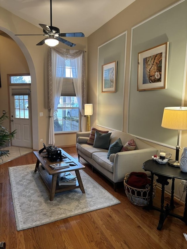 living area with a ceiling fan, arched walkways, and wood finished floors