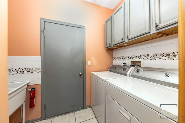 laundry room with cabinet space, light tile patterned floors, and separate washer and dryer