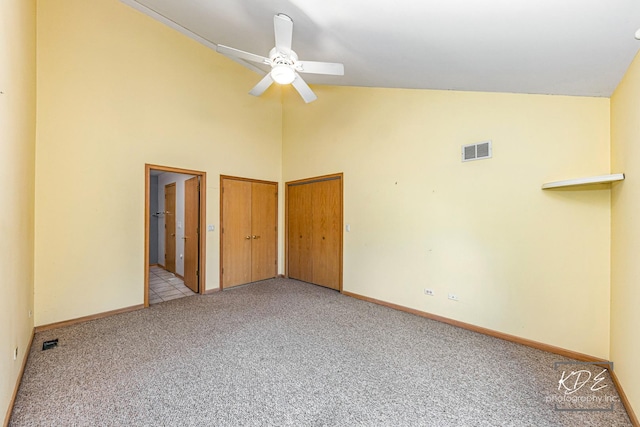 unfurnished bedroom featuring multiple closets, visible vents, carpet flooring, high vaulted ceiling, and baseboards