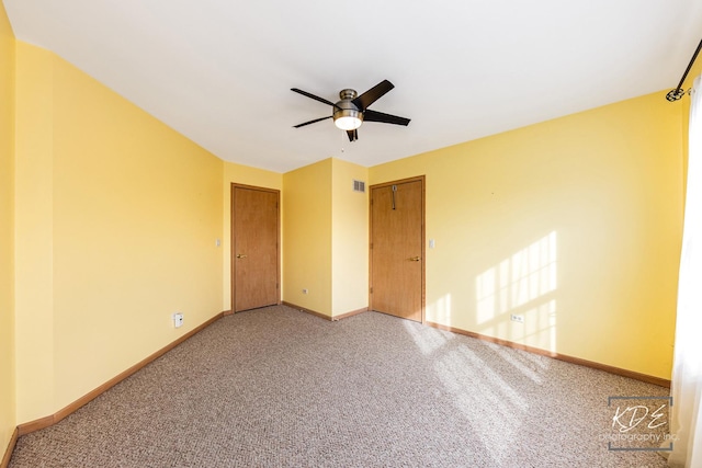 empty room featuring ceiling fan, carpet flooring, visible vents, and baseboards