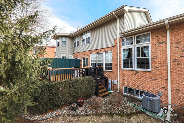 back of house with fence, a deck, central AC, and brick siding