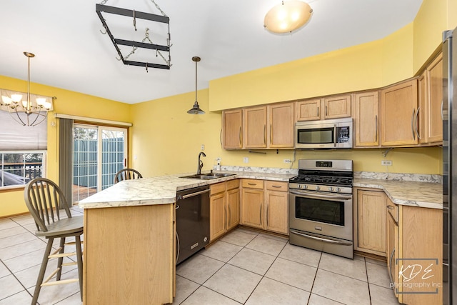 kitchen featuring stainless steel appliances, a peninsula, a sink, and light countertops