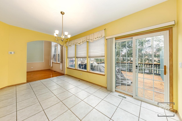 unfurnished dining area with light tile patterned floors, arched walkways, visible vents, and an inviting chandelier