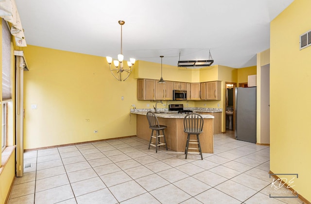 kitchen featuring appliances with stainless steel finishes, a kitchen breakfast bar, a peninsula, a notable chandelier, and a sink