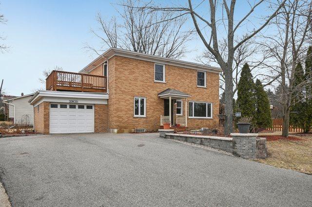 view of front of home with driveway, a balcony, and brick siding