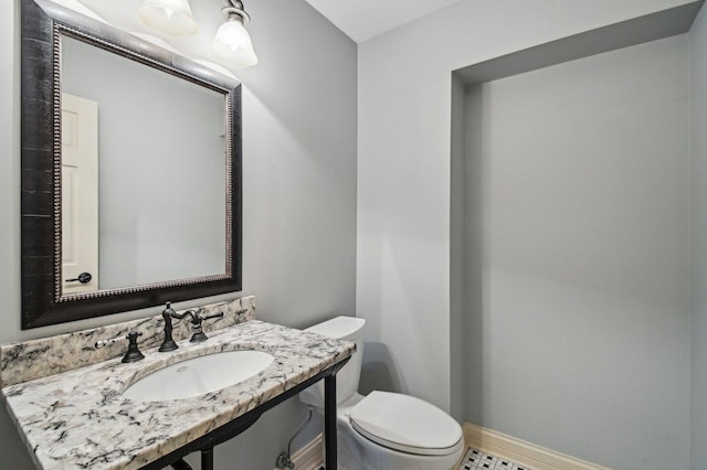 half bath with vanity, toilet, and baseboards