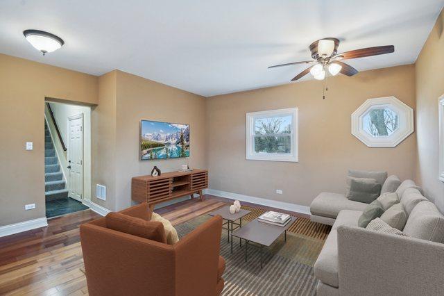 living room featuring ceiling fan, wood finished floors, visible vents, baseboards, and stairs