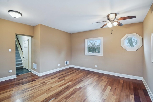 empty room with wood finished floors, visible vents, and baseboards