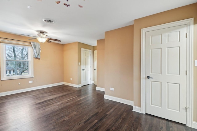 unfurnished room featuring a ceiling fan, dark wood-style flooring, visible vents, and baseboards