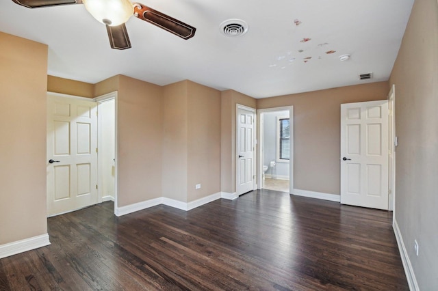 unfurnished room with dark wood-type flooring, visible vents, baseboards, and a ceiling fan