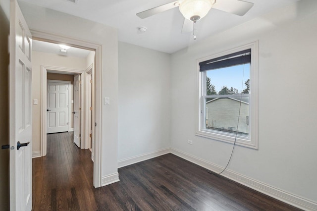 unfurnished room with dark wood-type flooring, a ceiling fan, and baseboards