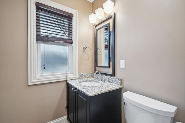 bathroom featuring toilet, vanity, and baseboards