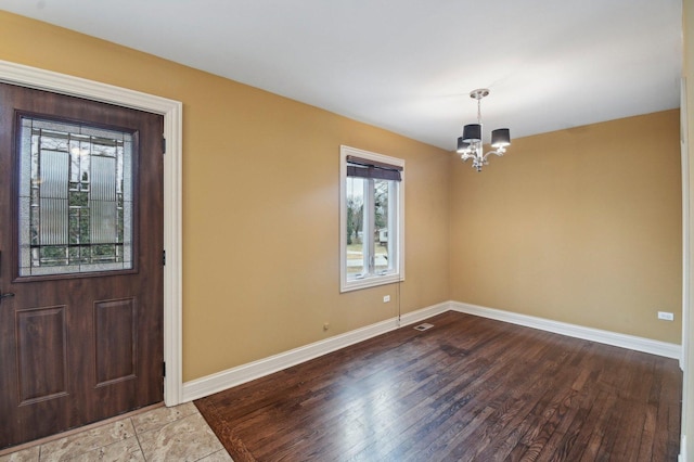 foyer entrance featuring baseboards, visible vents, a chandelier, and wood finished floors