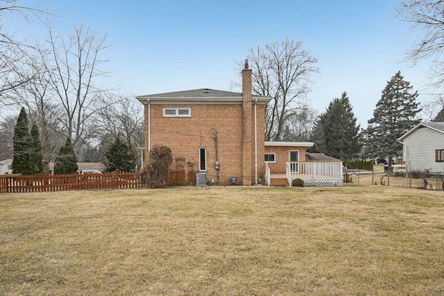 rear view of property with a chimney, fence, a deck, and a lawn