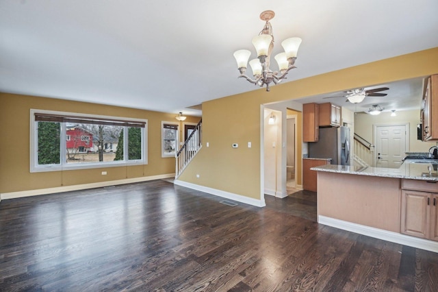 kitchen with dark wood-style flooring, visible vents, open floor plan, light stone countertops, and stainless steel fridge