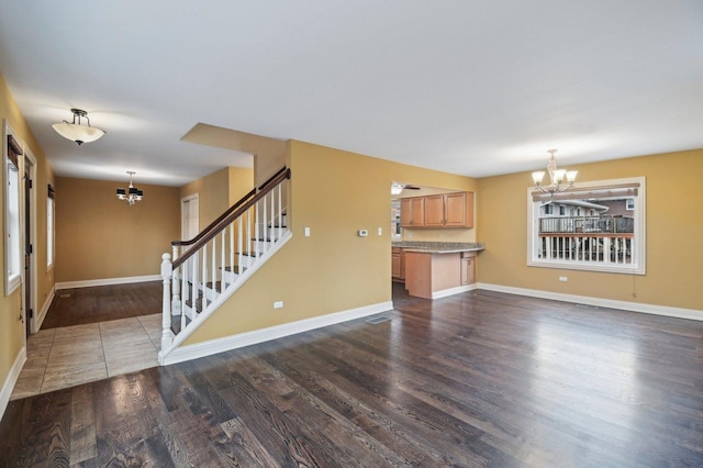 unfurnished living room featuring a chandelier, stairway, baseboards, and dark wood-style floors