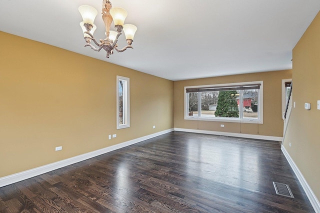 spare room featuring an inviting chandelier, baseboards, visible vents, and dark wood-style flooring