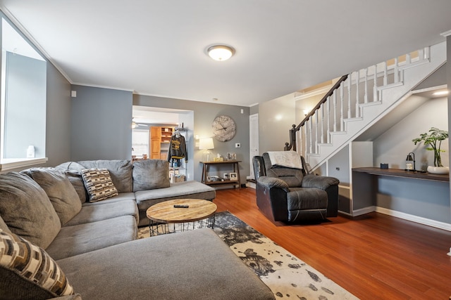 living area with baseboards, stairs, ornamental molding, and wood finished floors