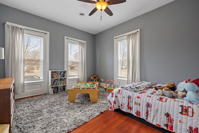 bedroom featuring ceiling fan, wood finished floors, and visible vents