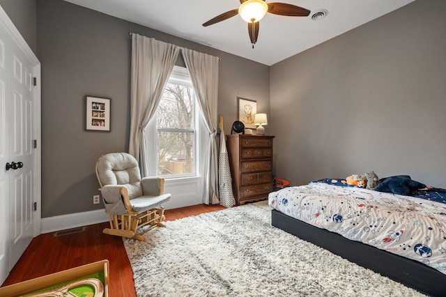 bedroom with a ceiling fan, baseboards, visible vents, and wood finished floors