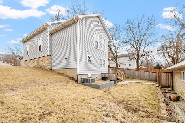 view of side of property featuring a yard, fence, and central air condition unit