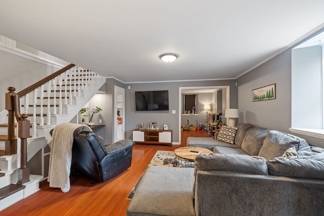 living area with crown molding, stairway, and wood finished floors