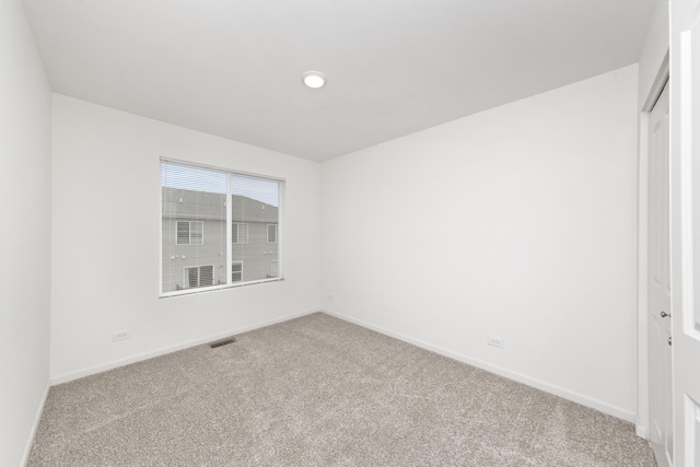 spare room featuring carpet, visible vents, and baseboards