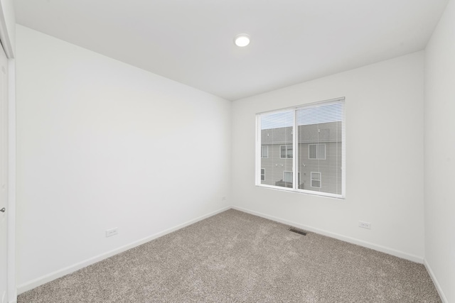 empty room featuring carpet, visible vents, and baseboards