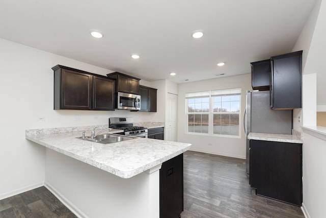 kitchen with light countertops, appliances with stainless steel finishes, dark wood-type flooring, dark brown cabinetry, and a sink