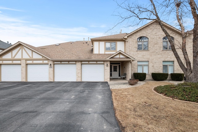 view of front of house with driveway, brick siding, roof with shingles, and an attached garage