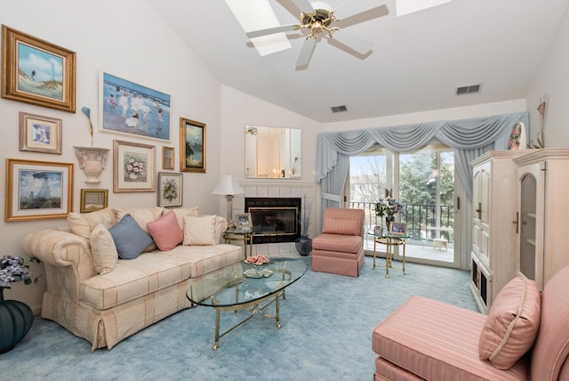 carpeted living room featuring high vaulted ceiling, ceiling fan, visible vents, and a tiled fireplace