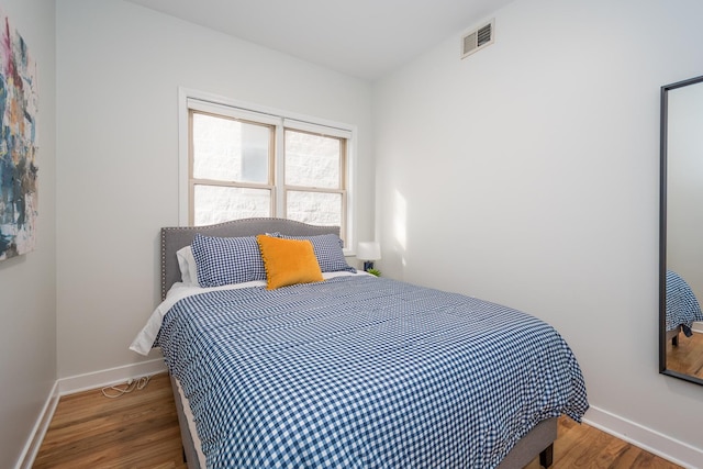 bedroom with visible vents, baseboards, and wood finished floors