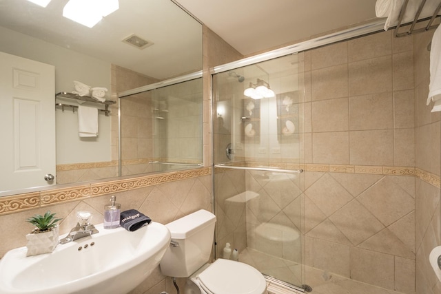 full bath with visible vents, toilet, a stall shower, a sink, and backsplash