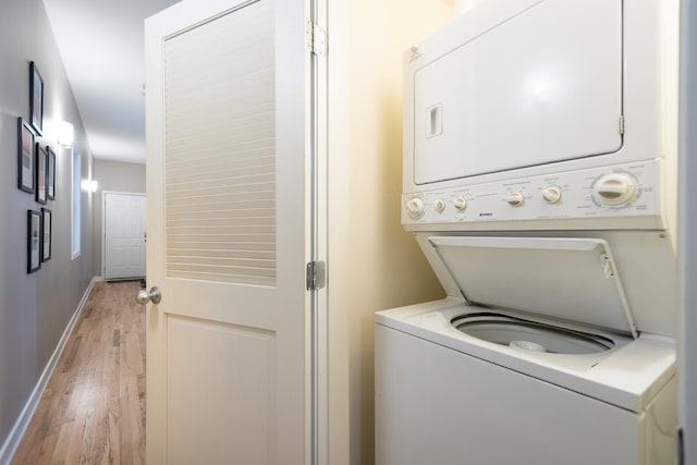 laundry room with laundry area, stacked washing maching and dryer, light wood-type flooring, and baseboards