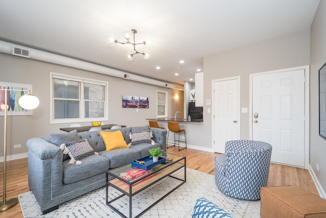 living room featuring light wood-style flooring, baseboards, and visible vents