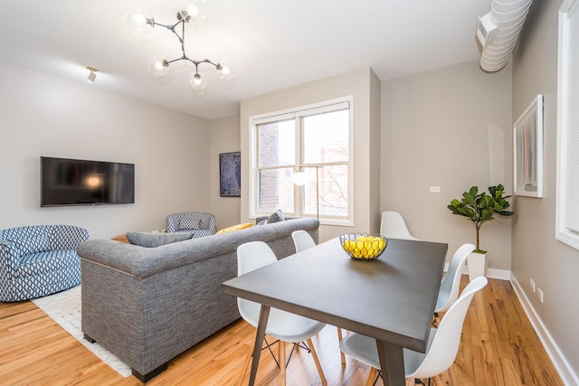 dining space with a chandelier, baseboards, and light wood-style flooring